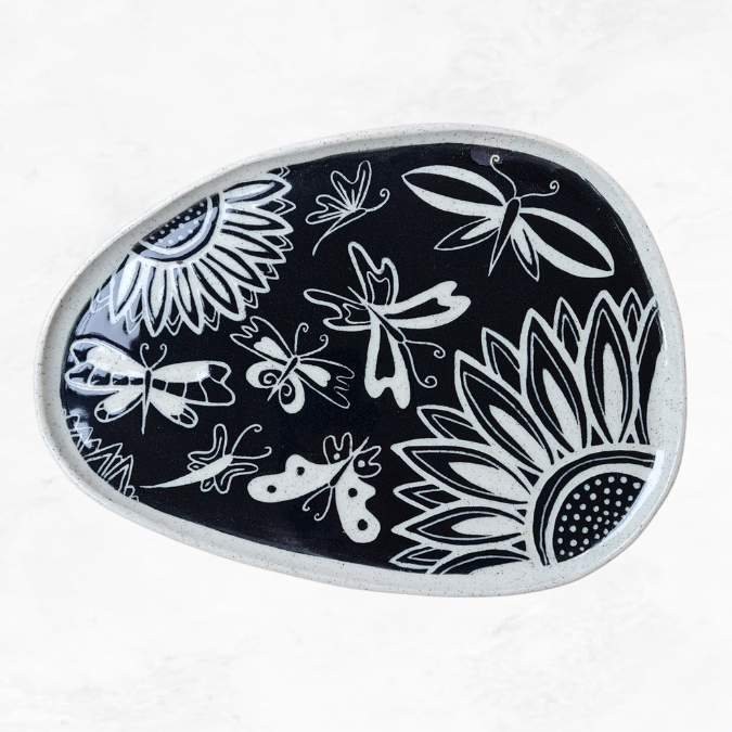 Ceramic plate, decorated with two half flowers, butterflies, black and white in colour.