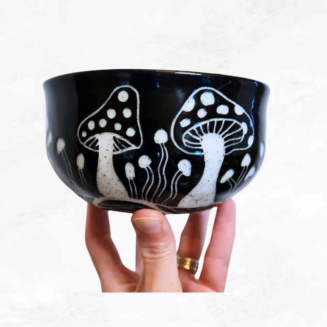 Ceramic bowel, decorated with mushrooms around the outside, black and white in colour.